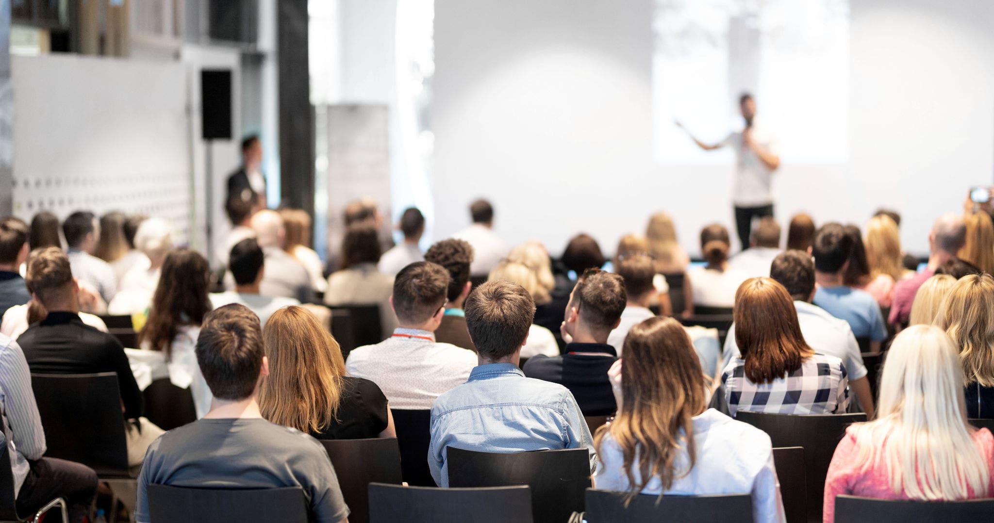 Speaker giving a talk in conference hall at business event. Audience at the conference hall. Business and Entrepreneurship concept. Focus on unrecognizable people in audience.-1117902230