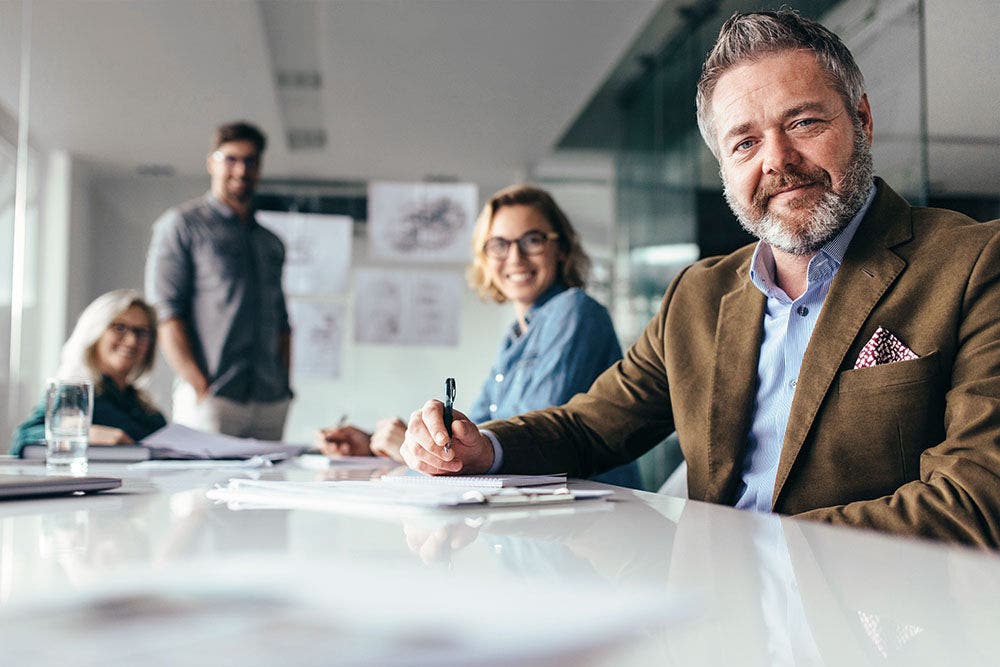 Businesspeople looking at camera with smile. Team of professionals sitting in boardroom.-681211219