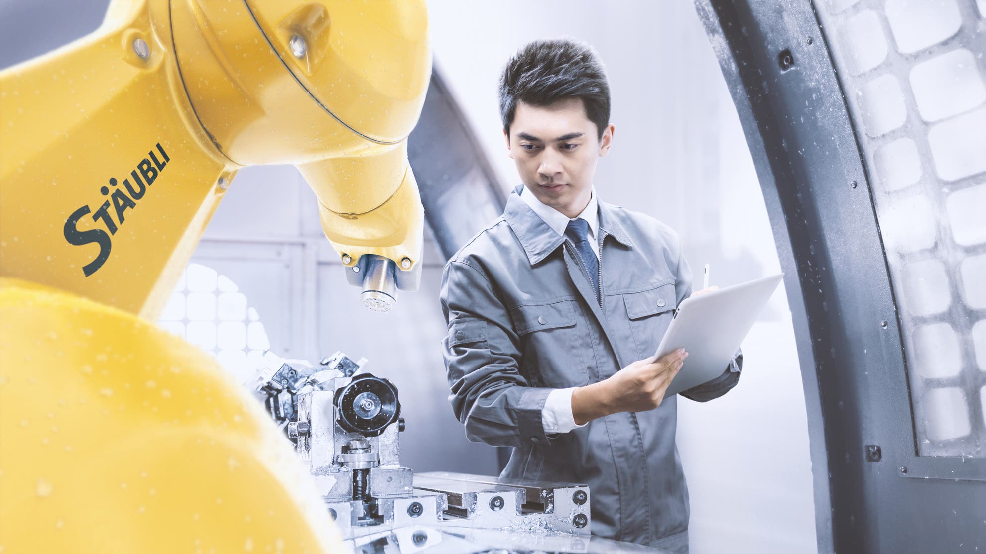 Industrial robot inside a computer numerical controlled (CNC) for machine tending application. An operator checks the quality.